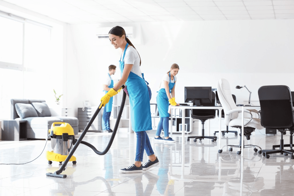 Cleaning crew vacuuming and wiping down a bright commercial office